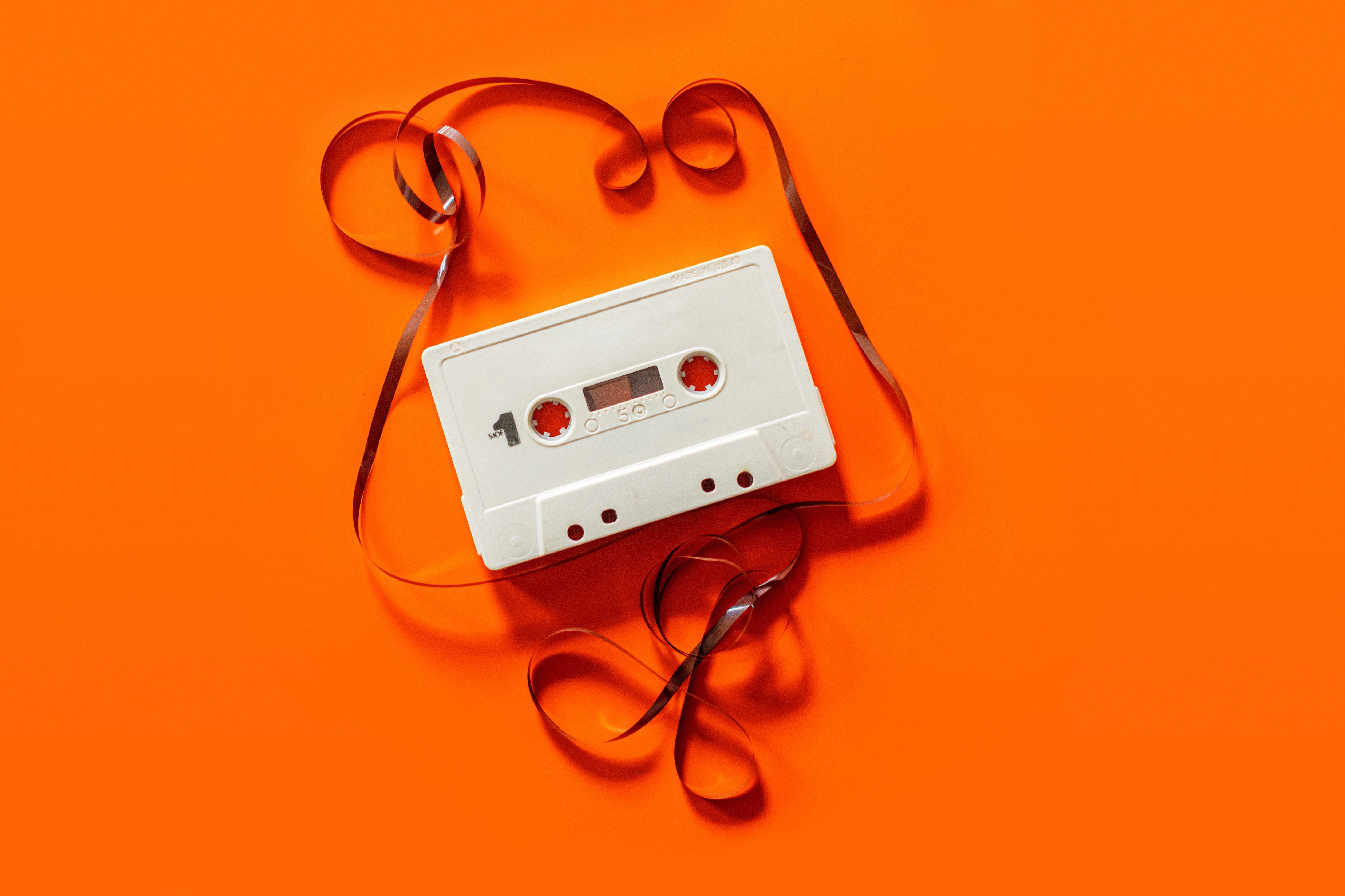 Cassette tape on orange background, symbolizing 1980s, the start of IT support services - Inderly IT