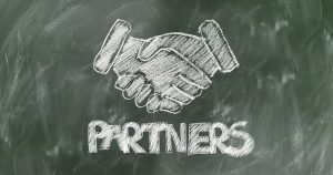 Shaking hands on blackboard over word "Partners"