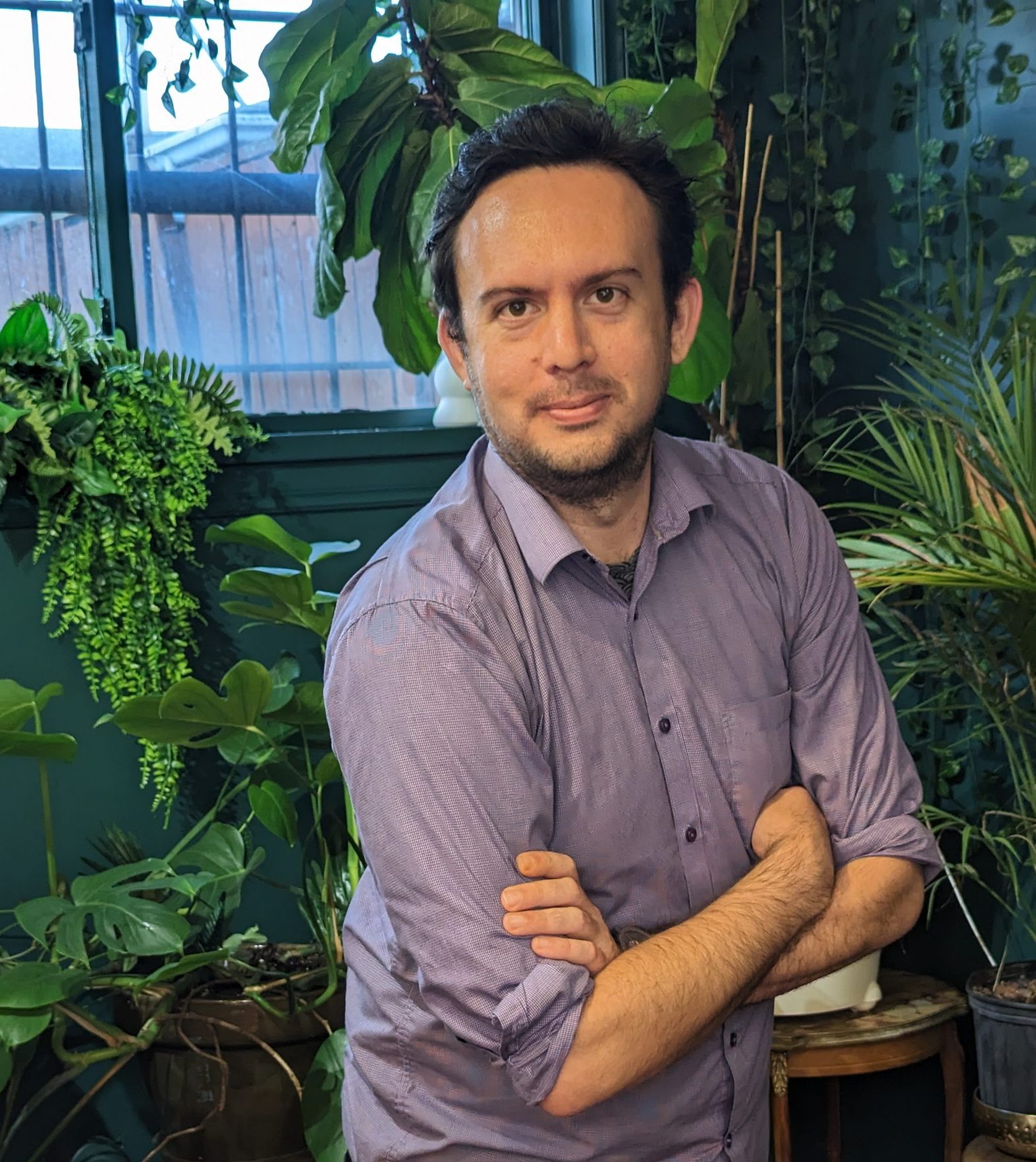 Photo of Nolan Witkowski, CEO of Inderly - IT for Law Firms, wearing purple shirt and standing in front of green indoor plants